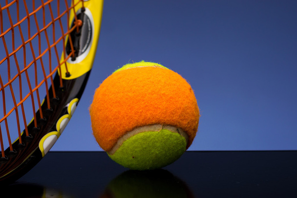 Bola de tênis para crianças com raquete de tênis em fundo azul
 - Foto, Imagem