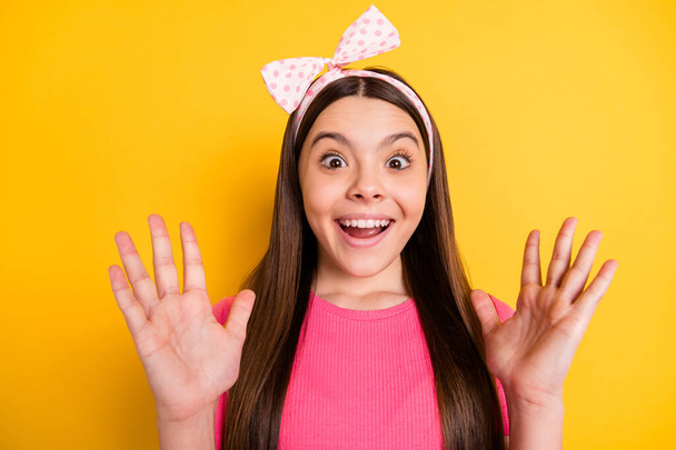 Photo of pretty excited small schoolgirl dressed pink t-shirt smiling rising arms isolated yellow color background - Φωτογραφία, εικόνα