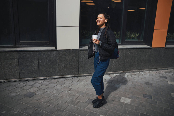 Happy lady with hot beverage standing in the street - Foto, Imagen