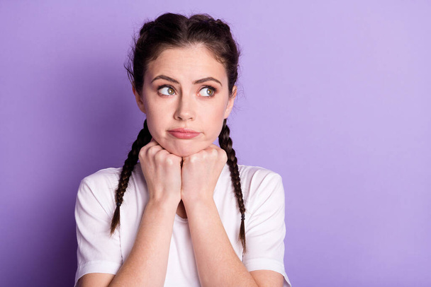 Photo of dreamy upset young woman look empty space hold fists chin think isolated on purple color background - Фото, изображение