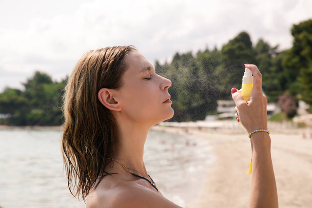 Mulher pulverizando névoa facial em seu rosto, conceito de cuidados com a pele verão - Foto, Imagem