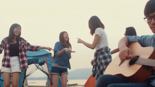 Beste Freunde Asiens Teenager geben High Five und tanzen bei Gitarrenmusik fröhliche Momente zusammen neben Zelten im Nationalpark. Im Hintergrund schöne Natur, Berge und See. - Filmmaterial, Video