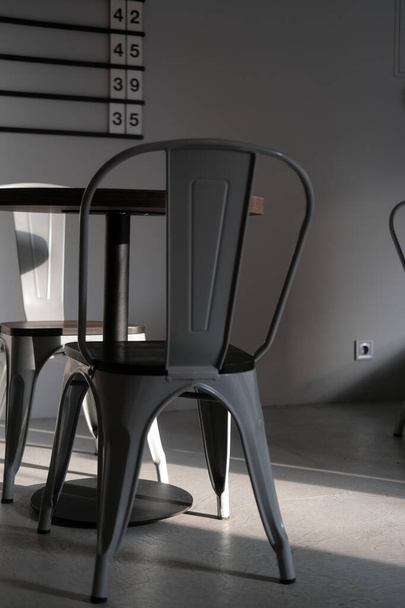 Moderna silla de metal de color gris loft en la cafetería. Interior creativo detalle foto en luces y sombras. Concepto minimalista, estilo de vida, primer plano - Foto, imagen