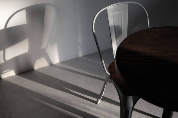 Μοντέρνα σοφίτα γκρι χρώμα μεταλλική καρέκλα σε καφετέρια. Δημιουργική φωτογραφία εσωτερική λεπτομέρεια σε φώτα και σκιές. Minimalist concept, lifestyle, κοντινό - Φωτογραφία, εικόνα