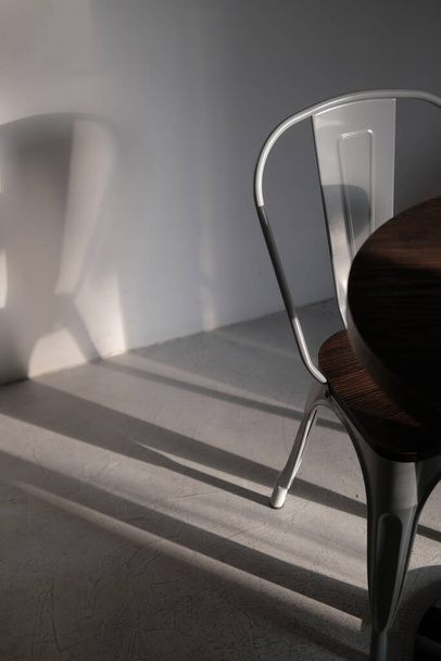 Chaise moderne en métal de couleur grise loft au café. Photo de détails intérieurs créatifs dans les lumières et les ombres. Concept minimaliste, style de vie, gros plan - Photo, image