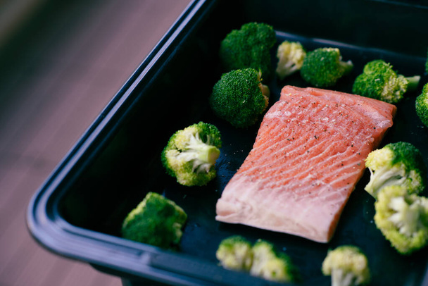 Świeże organiczne filety z łososia atlantyckiego na tacy do pieczenia z zielonymi brokułami jako zdrowe odżywianie i dieta keto - Zdjęcie, obraz