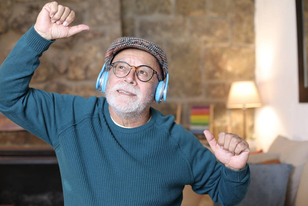 közeli kép jóképű idős férfi zenét hallgat fejhallgatóval otthon - Fotó, kép