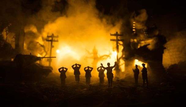 Militärische Silhouetten kämpfen Szene auf Krieg Nebel Himmel Hintergrund. Ein deutscher Soldat erhob die Waffen, um sich zu ergeben. Spielzeugsoldaten aus Plastik mit Gewehren, die den feindlichen Soldaten gefangen nehmen. Selektiver Fokus - Foto, Bild