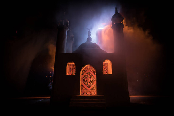 Una mezquita realista en miniatura con ventanas por la noche. Tarjeta de felicitación festiva, invitación para el mes sagrado musulmán Ramadán Kareem. Enfoque selectivo - Foto, imagen