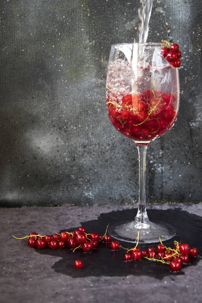 Fresh red currants in a wine glass on a gray background - Foto, immagini