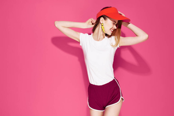 alegre bonita mujer en rojo cap verano ropa moda posando rosa fondo - Foto, Imagen