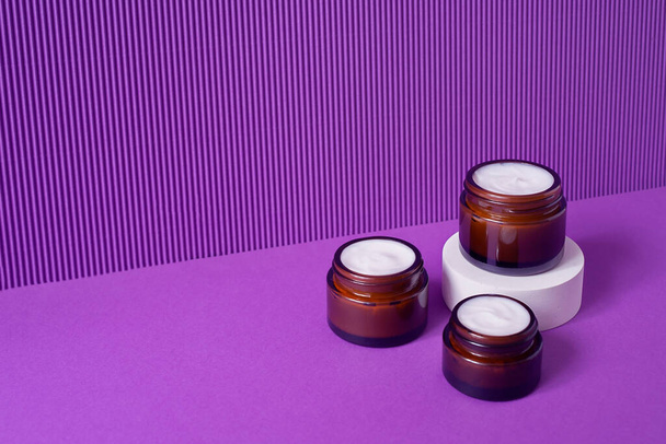 Три янтарные стеклянные банки с модной геометрической формой на фиолетовом фоне. - Фото, изображение