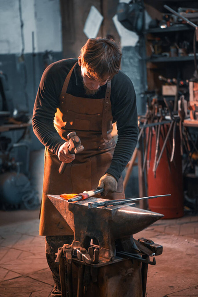 Blacksmith is working on an anvil, forging a red-hot metal blank. - Fotoğraf, Görsel