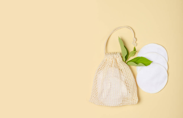 Cotton reusable makeup remover pads in a cloth bag on a beige background. The concept of ecology and conscious consumption. Reusable cotton pads - Photo, Image