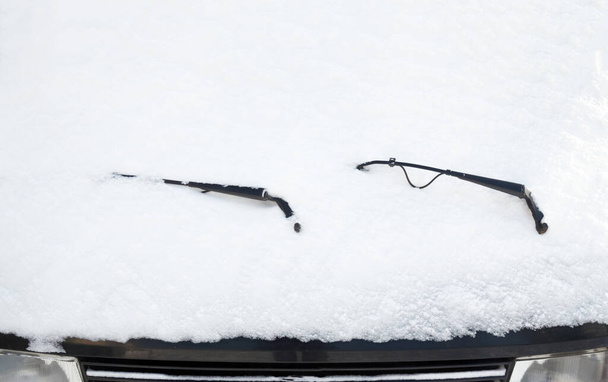 A parkoló autó ablaktörlőit és szélvédőjét hó borítja. Közelkép. - Fotó, kép