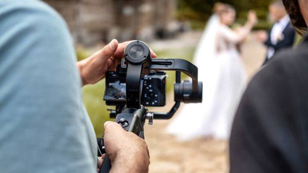 三脚にカメラを使って結婚式を記録するカメラマン - 写真・画像