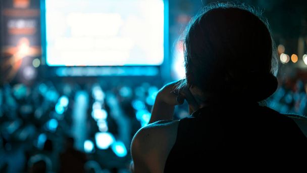 Istuva nainen katsomassa jalkapalloa julkisella paikalla yöllä - Valokuva, kuva