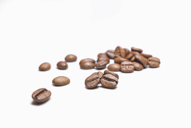 Scattered beans of medium roast coffee on a white background. Arabica roast coffee beans. Toning drink, natural energetic. Beans closeup, morning aroma. Space for text. - Foto, Imagen