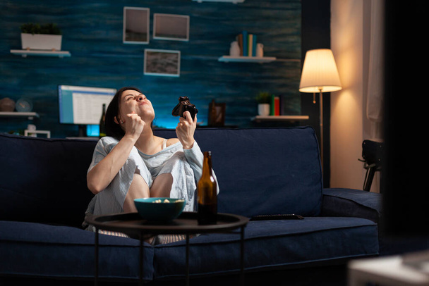 Žena hráč hraje videohry s joystick sedí na pohovce v obývacím pokoji - Fotografie, Obrázek
