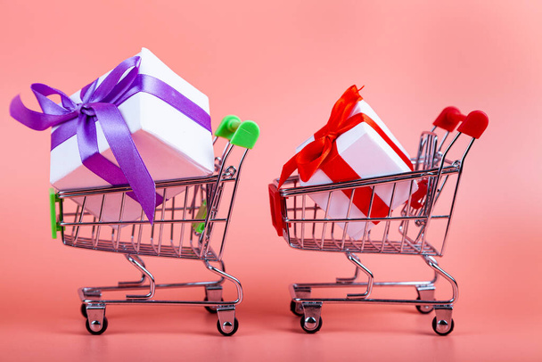 Shopping carts and gifts on a pink background. Concept: buying gifts. - Fotoğraf, Görsel