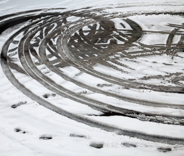 Ίχνη τροχών στον χειμερινό δρόμο καλυμμένα με χιόνι. Υγρό χιόνι. Απόψυξη. - Φωτογραφία, εικόνα