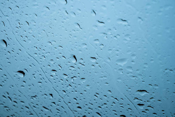 Raindrops on glass window over grey and blue sky - Foto, Imagen