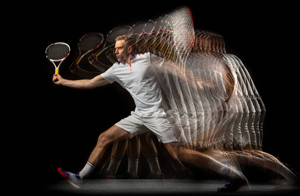 Portrait of young man, male tennis player in motion and action isolated on dark background. Stroboscope effect. - Foto, afbeelding