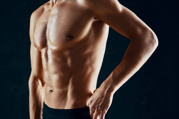 uomo sportivo con un corpo muscoloso pompato in un asciugamano sfondo scuro - Foto, immagini