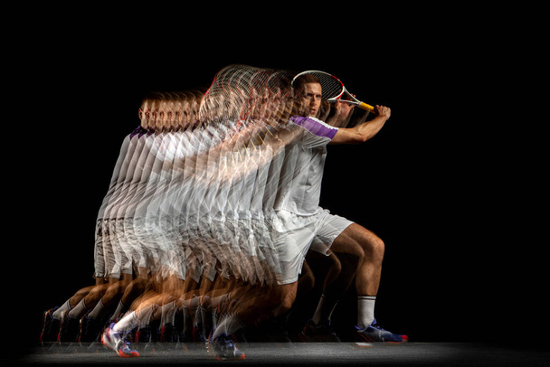Macht en snelheid. Jongeman, professionele tennisser in beweging en actie geïsoleerd op donkere achtergrond met stroboscoop effect. - Foto, afbeelding