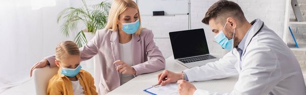 Mother in protective mask pointing at kid near pediatrician writing on clipboard, banner  - Fotoğraf, Görsel