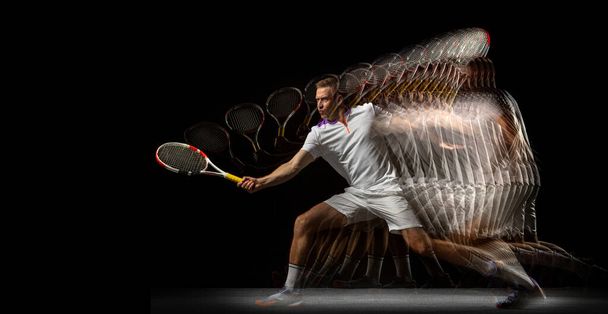 Portrait of young man, male tennis player in motion and action isolated on dark background. Stroboscope effect. - Фото, изображение