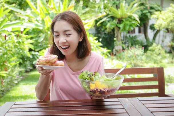 Mujer asiática de 40 años tiene una sonrisa brillante Cara joven, cuerpo sano Feliz de comer. concepto de cuidado de la salud, comer alimentos saludables - Foto, Imagen
