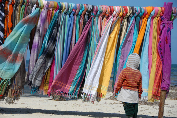 Verkaufsstand mit bunten Tüchern am Strand von Mombassa mit Kind im Vordergrund - Foto, imagen