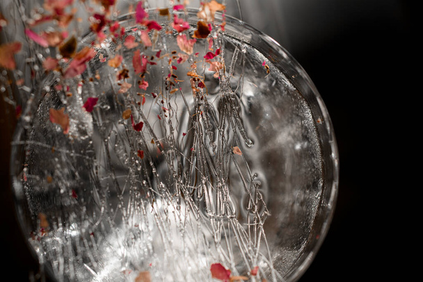Nahaufnahme von Karamellsträngen mit Blütenblättern als Glasdekoration - Foto, Bild