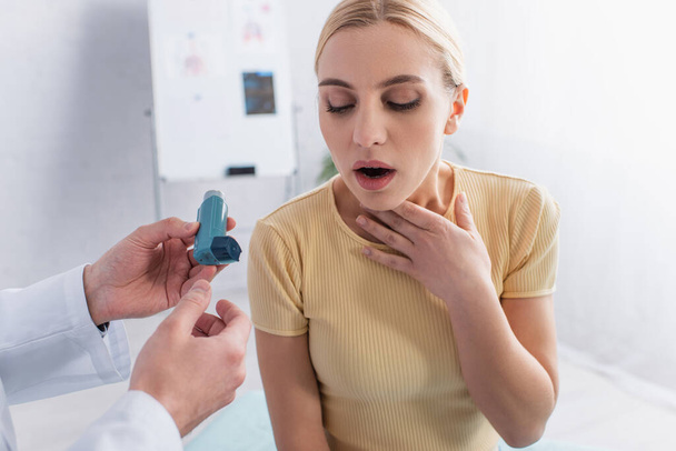 лікар тримає інгалятор біля жінки, торкаючись горла, страждаючи від астми
 - Фото, зображення