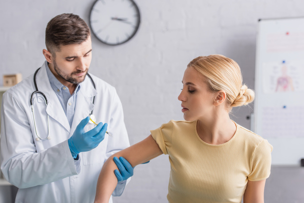 Arzt in Latexhandschuhen verabreicht Frau Impfstoff - Foto, Bild