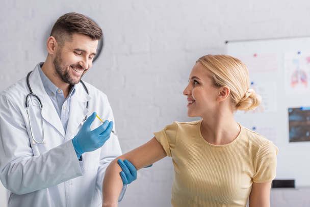 lekarz w rękawiczkach lateksowych szczepiący szczęśliwą kobietę w klinice - Zdjęcie, obraz