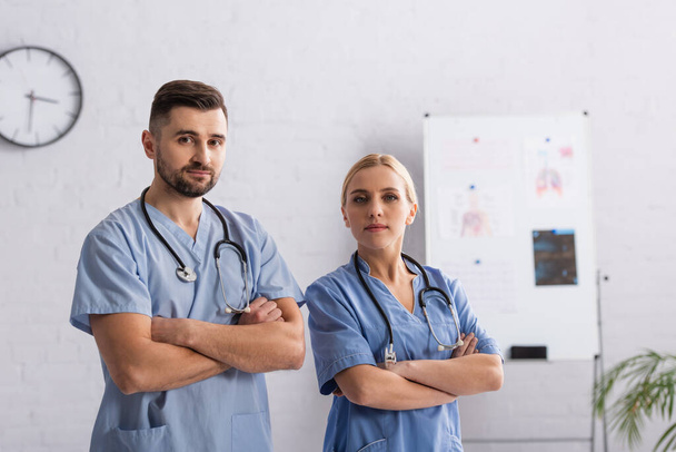 médecins en uniforme bleu regardant la caméra debout avec les bras croisés - Photo, image