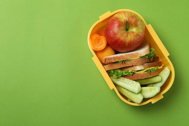 Обеденная коробка с вкусной едой на зеленом фоне - Фото, изображение