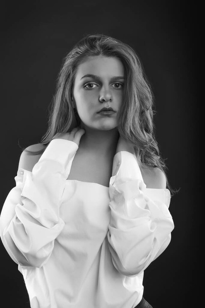 Fashionable young woman wears men's shirt posing in the shadows at studio. Black and white image - Fotografie, Obrázek