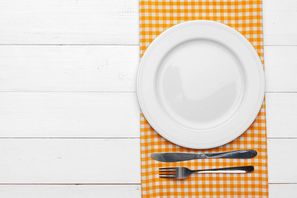 Empty plate and towel over wooden table background. - Foto, afbeelding