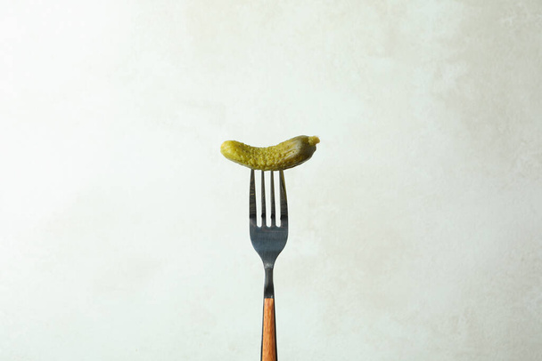 Fork with fresh pickle on white textured background - Фото, изображение