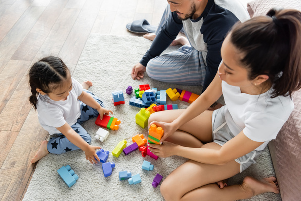 high angle view of asian parents playing building blocks with toddler girl on carpet - Fotoğraf, Görsel