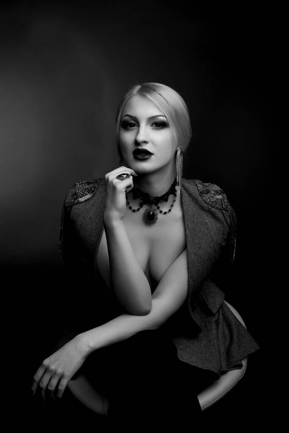 Stilvolles schwarz-weißes Studioporträt einer schönen Frau mit hellem Make-up trägt Jacke auf nacktem Körper - Foto, Bild