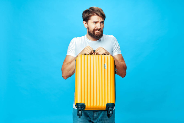 bearded man yellow suitcase passenger airport blue background - Foto, Imagen
