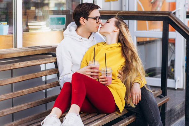 Loving couple kisses on a bench with coffee in their hands. - Foto, imagen