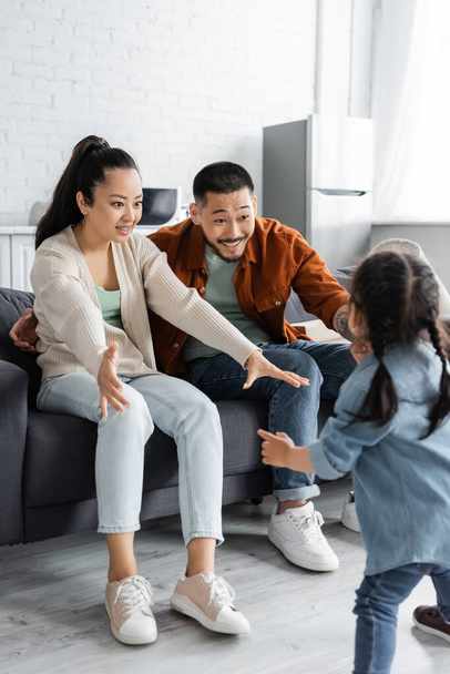 happy asian family looking at kid in modern living room - Foto, Imagem