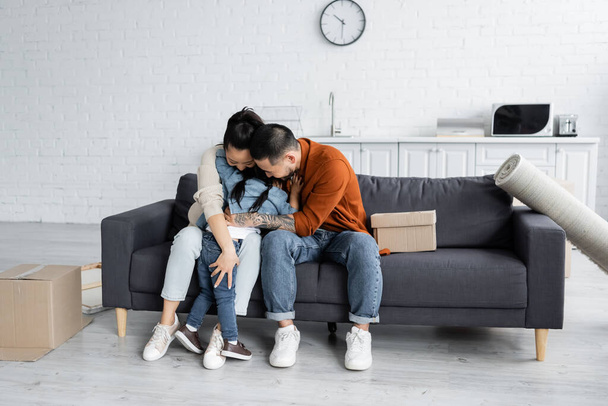 asian family embracing near boxes in new home  - Foto, imagen