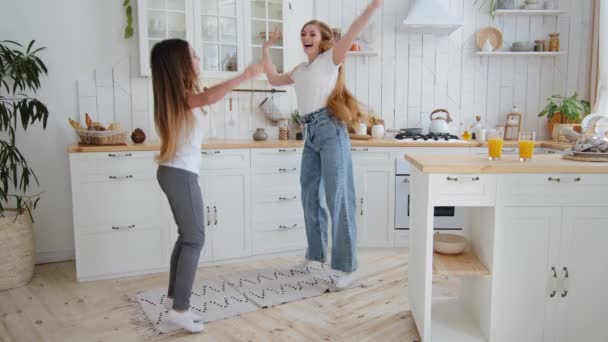 gelukkig meisje tiener kind schoolmeisje dochter hebben plezier met geliefde alleenstaande moeder volwassen vrouw moeder babysitter met lang haar dansen in huis keuken springen naar muziek spinnen als vliegtuig lachen - Video