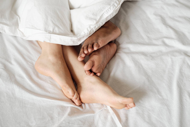 Bare feet of multiracial females lying in bed - Photo, image
